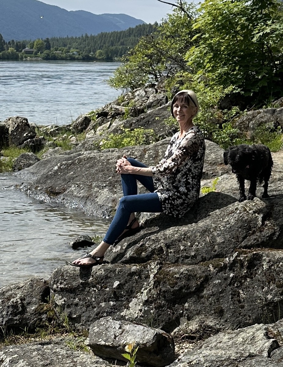 Becca sitting by the lake with her dog